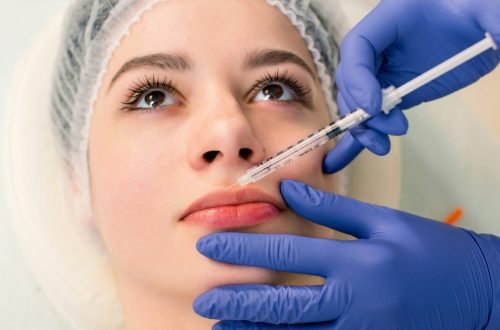 A beautiful woman receives a filler injection on the lips. Young woman receiving a botox injection
